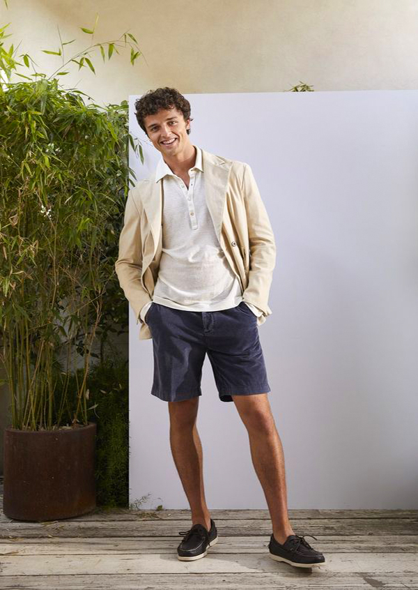Beige double-breasted blazer, white polo neck sweater, navy shorts, black boat shoes outfit