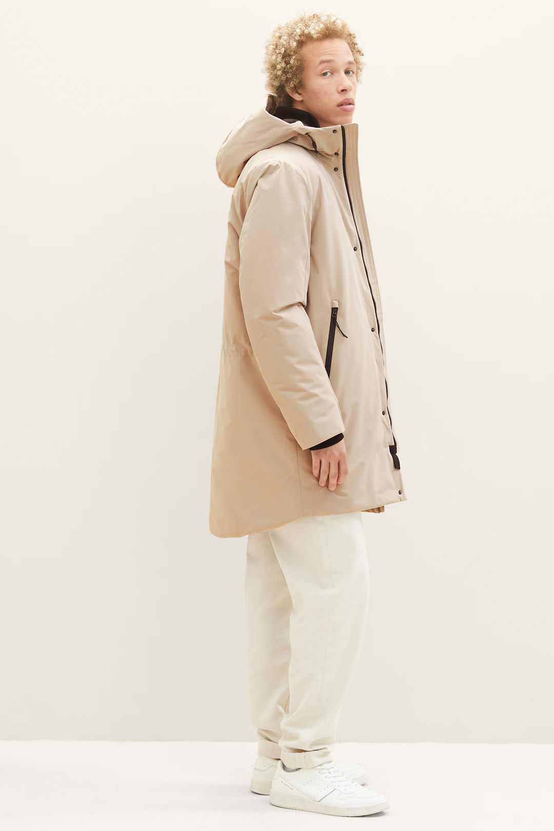 Beige hooded parka, cream off white pants, and white sneakers outfit