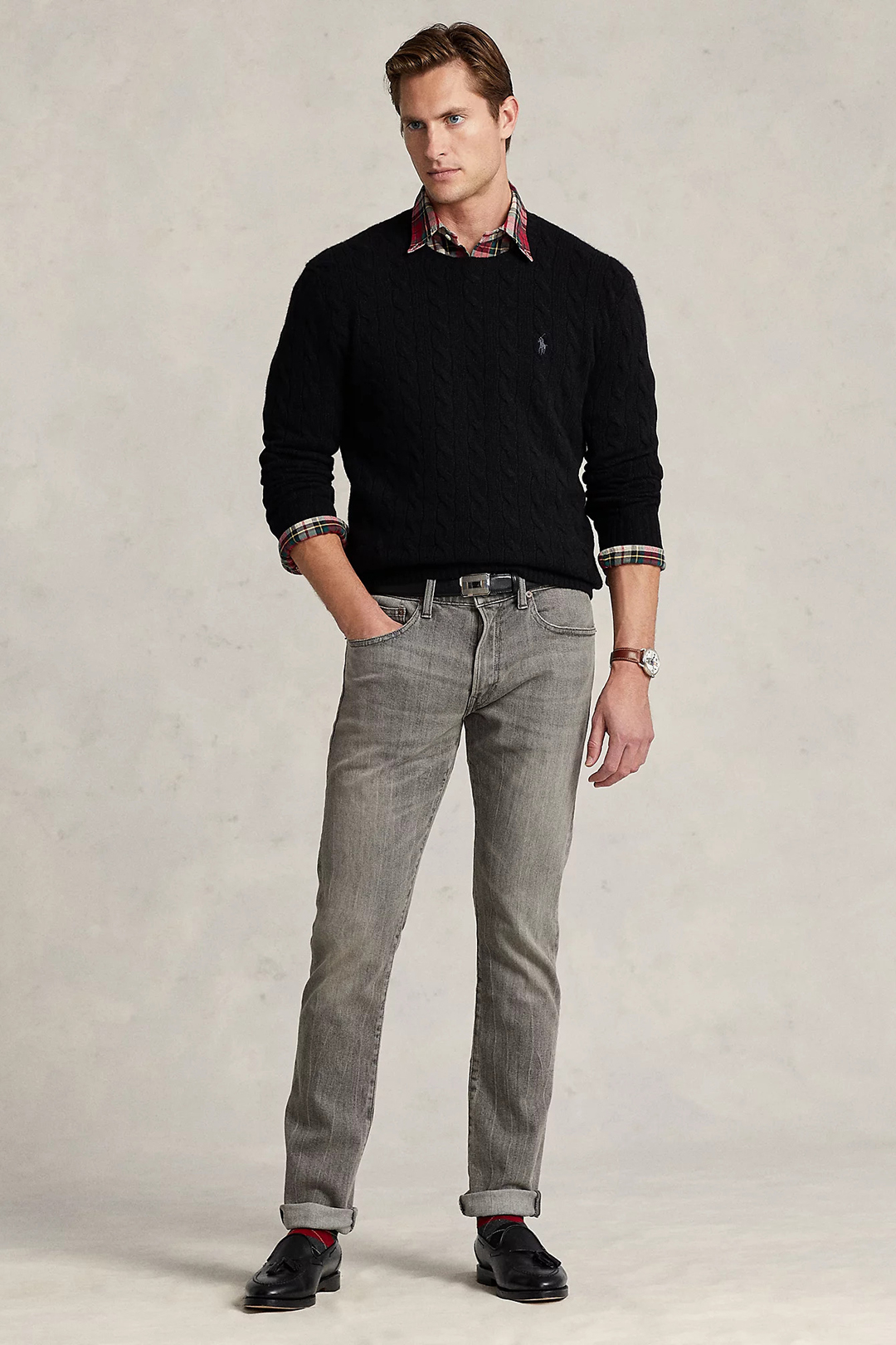 Black sweater over multi-color plaid shirt, gray jeans, and black tassel loafers outfit