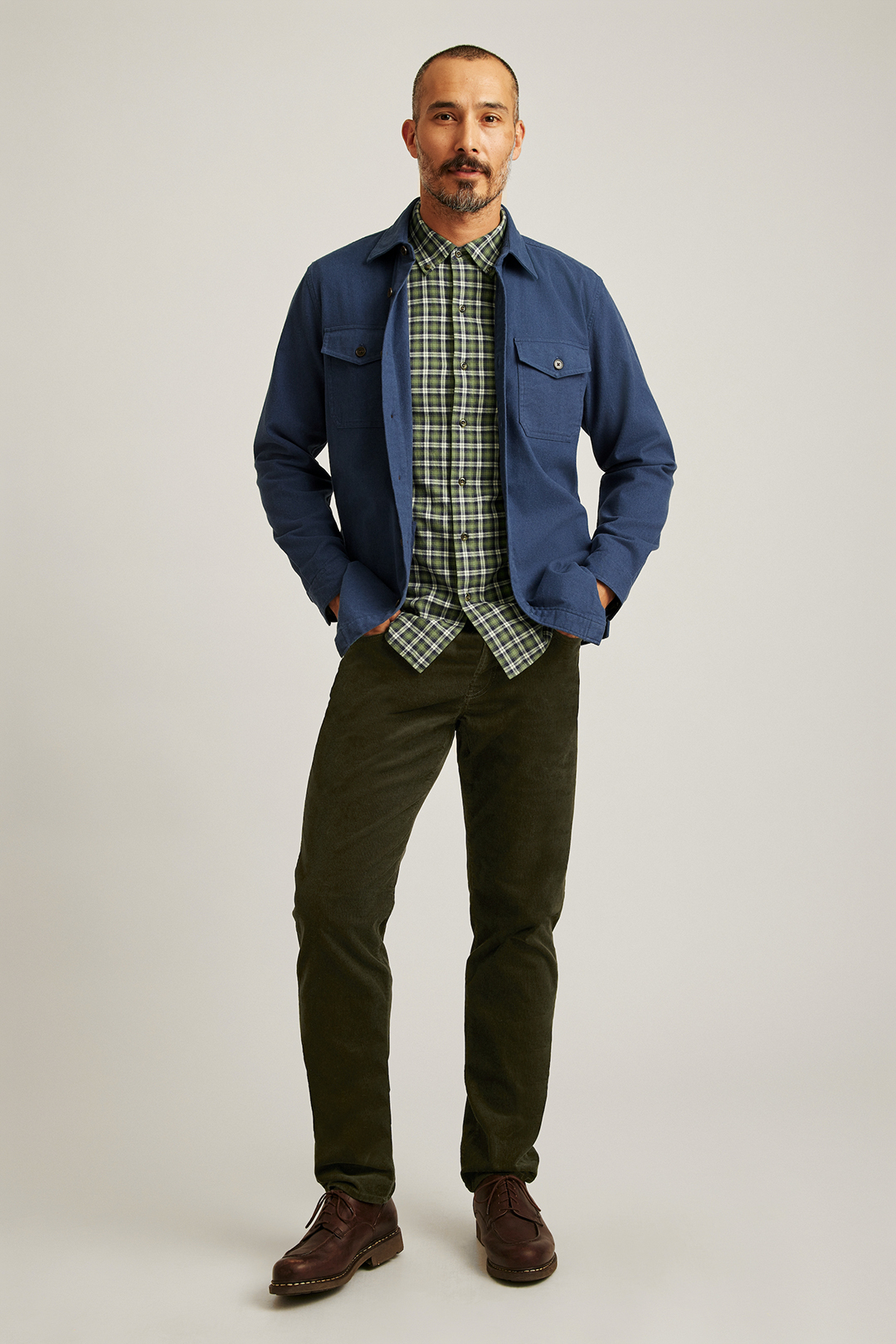 Blue overshirt, green plaid shirt, green corduroy jeans, and brown casual boots outfit