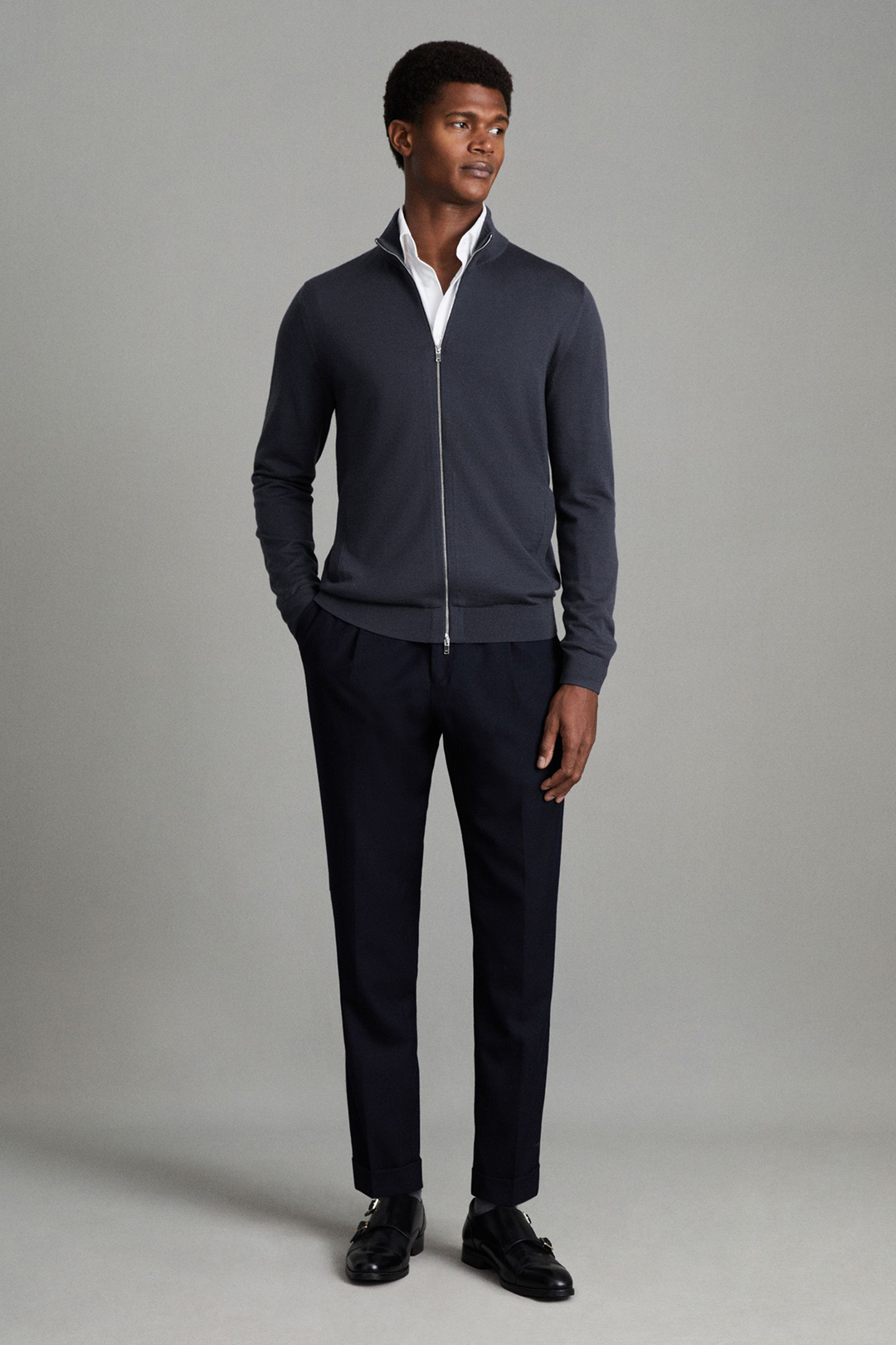 Blue zip front cardigan sweater, white dress shirt, navy chinos, and black double monks outfit