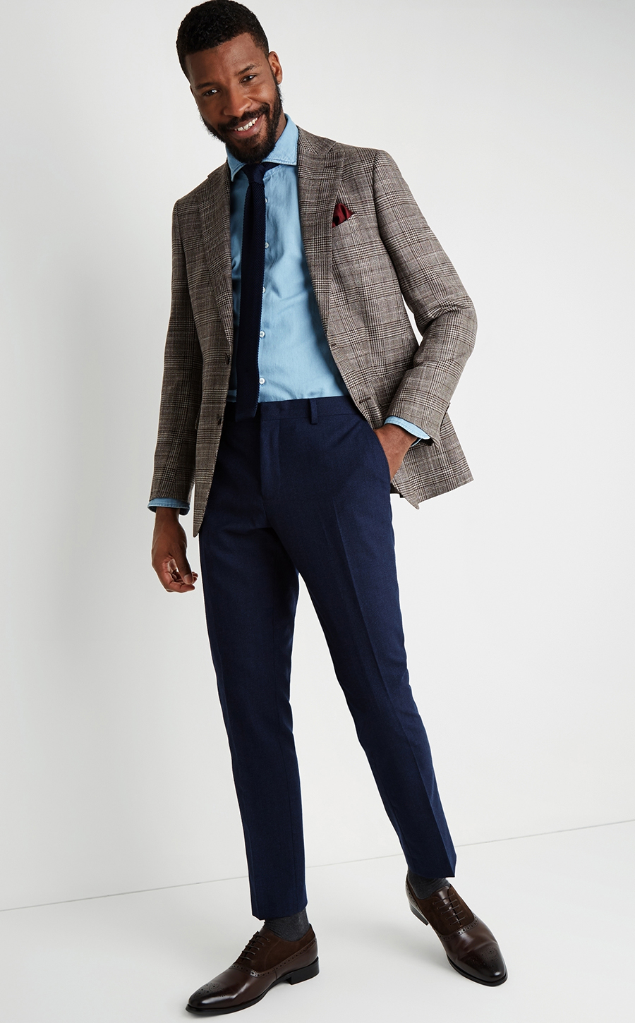 Brown houndstooth blazer, blue denim shirt, navy dress pants, navy knit tie, and brown oxfords outfit