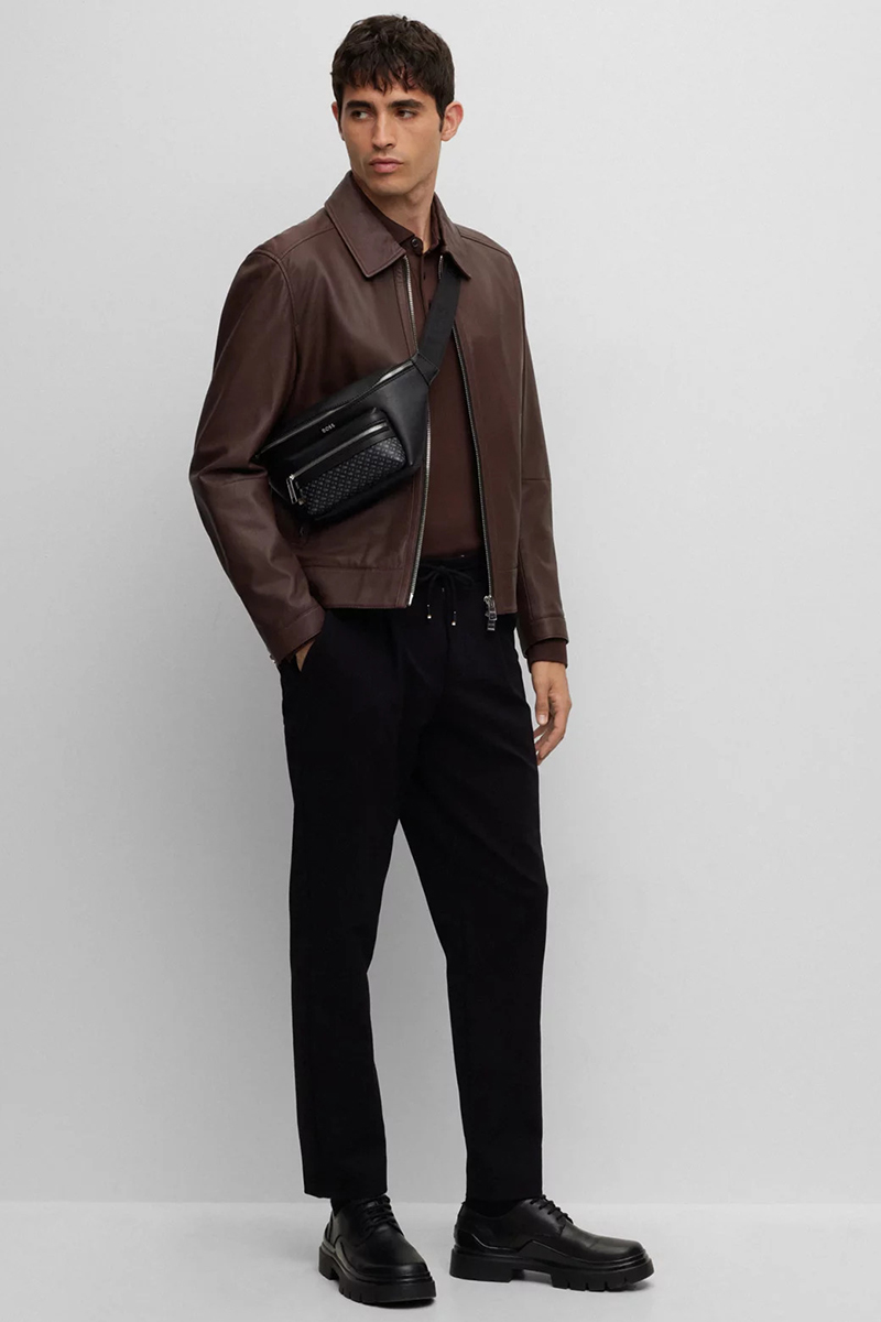 Brown leather jacket, brown polo shirt, navy drawstring trousers, and black derby shoes outfit