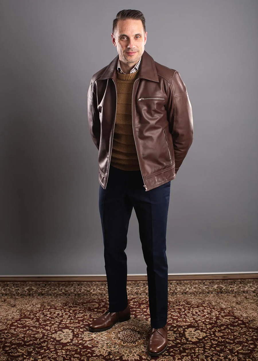Brown leather jacket with navy dress pants and brown Derby shoes