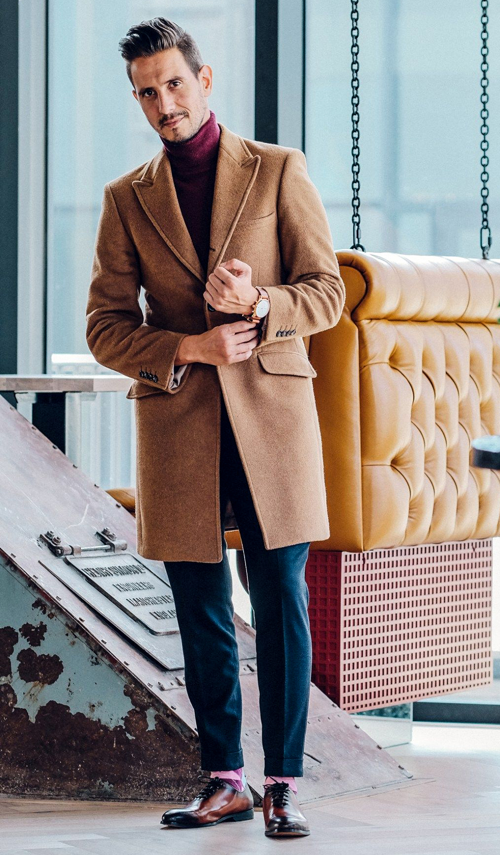 Burgundy turtleneck, camel overcoat, navy blue pants, and brown leather oxford shoes outfit
