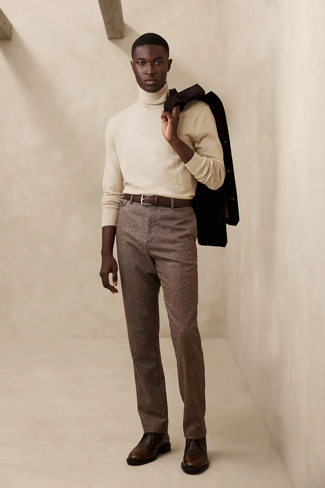 Charcoal shirt jacket, cream turtleneck, brown tweed dress pants, and brown chukka boots outfit