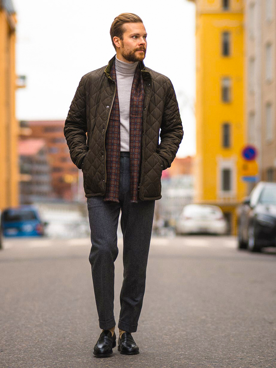 Dark green quilted jacket, light gray turtleneck, gray trousers, and black loafers outfit