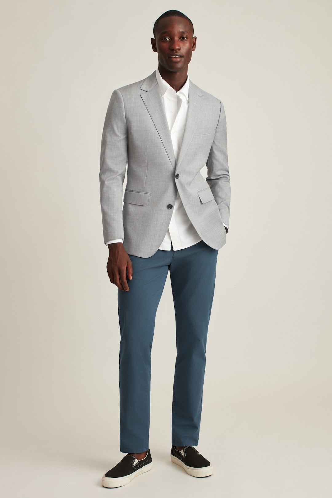 Gray blazer, white dress shirt, blue dress pants, and navy sneaker loafers outfit