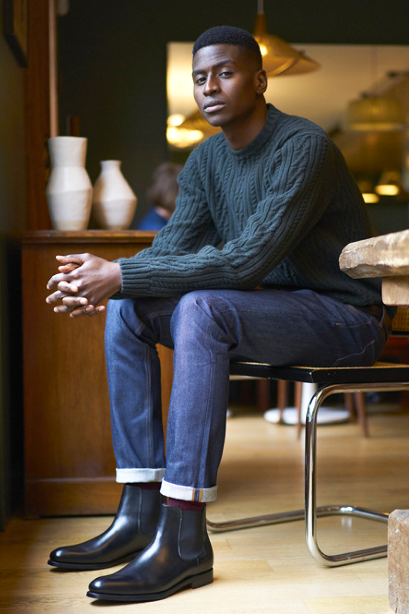 Man wearing black Chelsea boots with cuffed blue jeans and light blue sweater