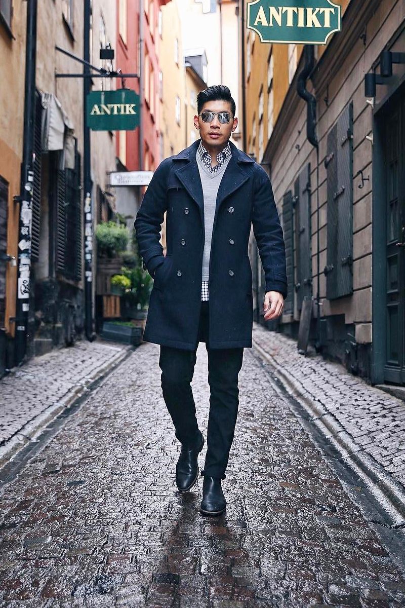 Navy overcoat, grey crew neck sweater, white and navy check long sleeve shirt, navy chinos, and black Chelsea boots outfit
