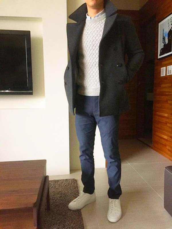 White cable sweater, black overcoat, navy pants, and white low-top sneakers outfit