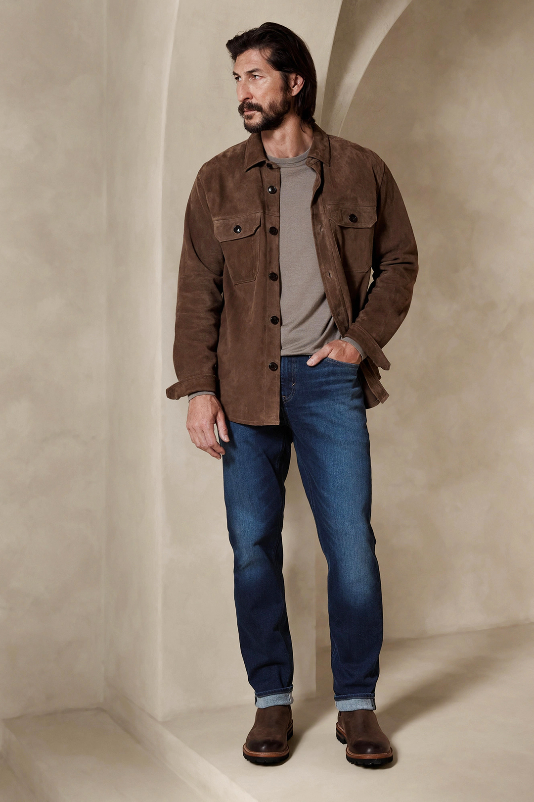Wear brown suede jacket, grey crew neck sweater, blue denim jeans, and brown Chelsea boots