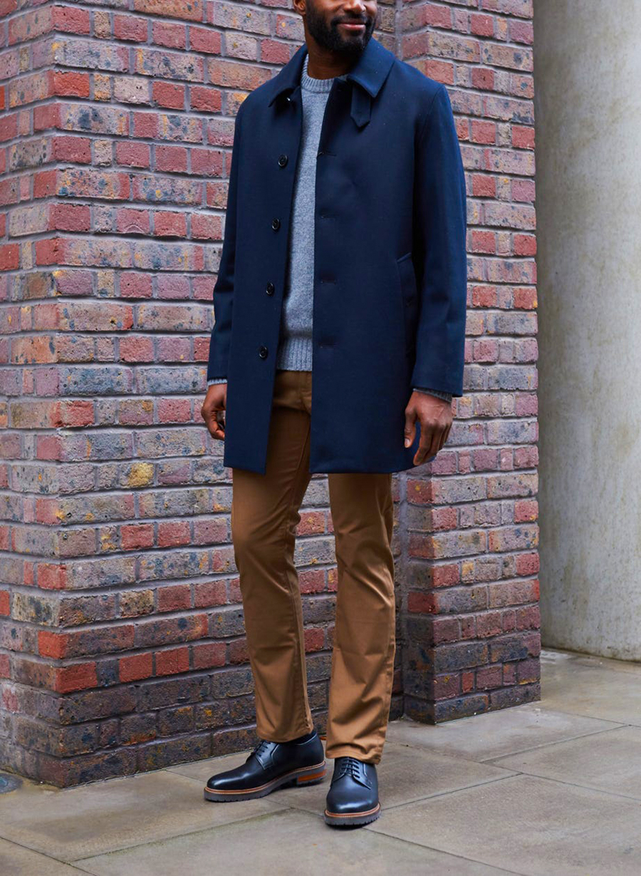 Wear navy trenchcoat, khaki chinos, sweater, and black derbies