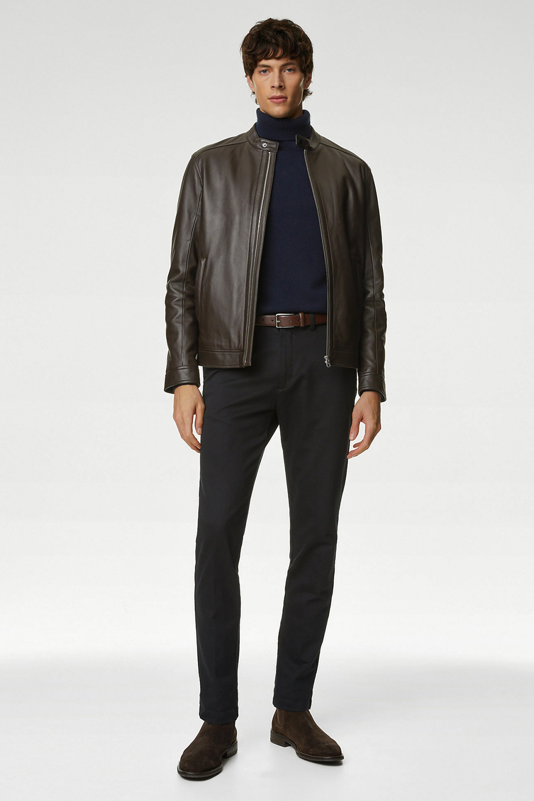 Wearing a brown leather biker jacket, navy turtleneck, black chinos, and dark brown suede Chelsea boots