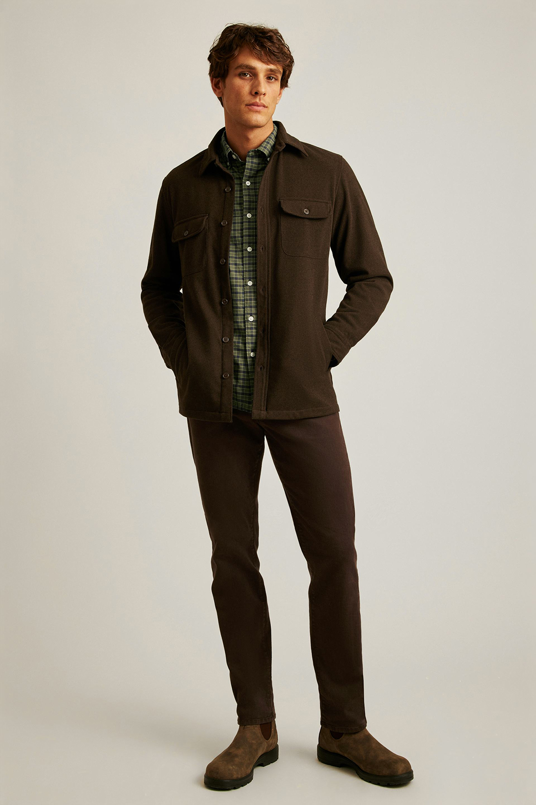 Wearing a brown overshirt, green plaid shirt, brown jeans, and brown suede Chelsea boots
