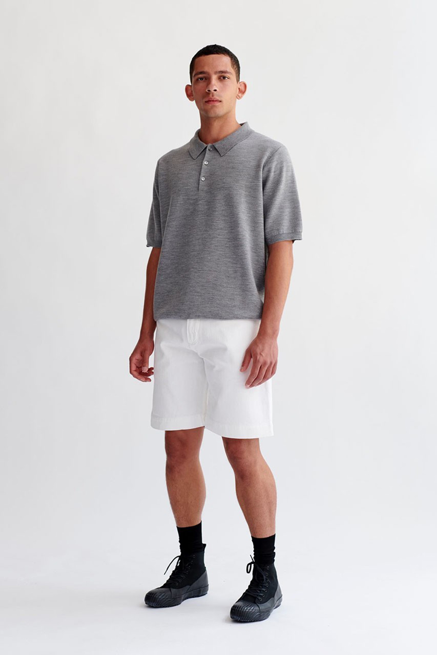 Wearing a gray polo, white shorts, and black high top sneakers