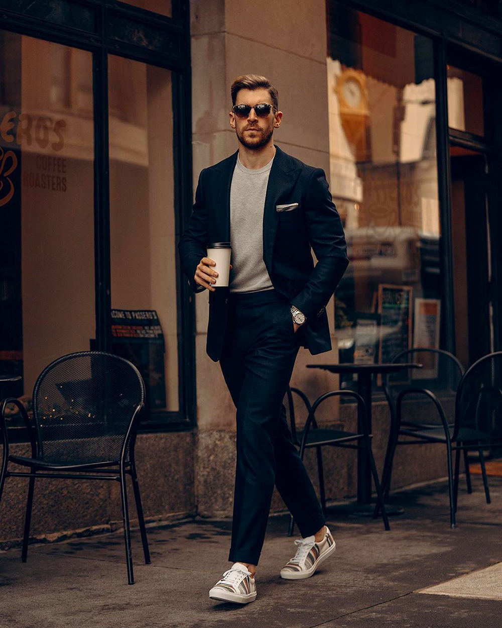 Wearing a navy suit, gray long sleeve t-shirt, and low top sneakers