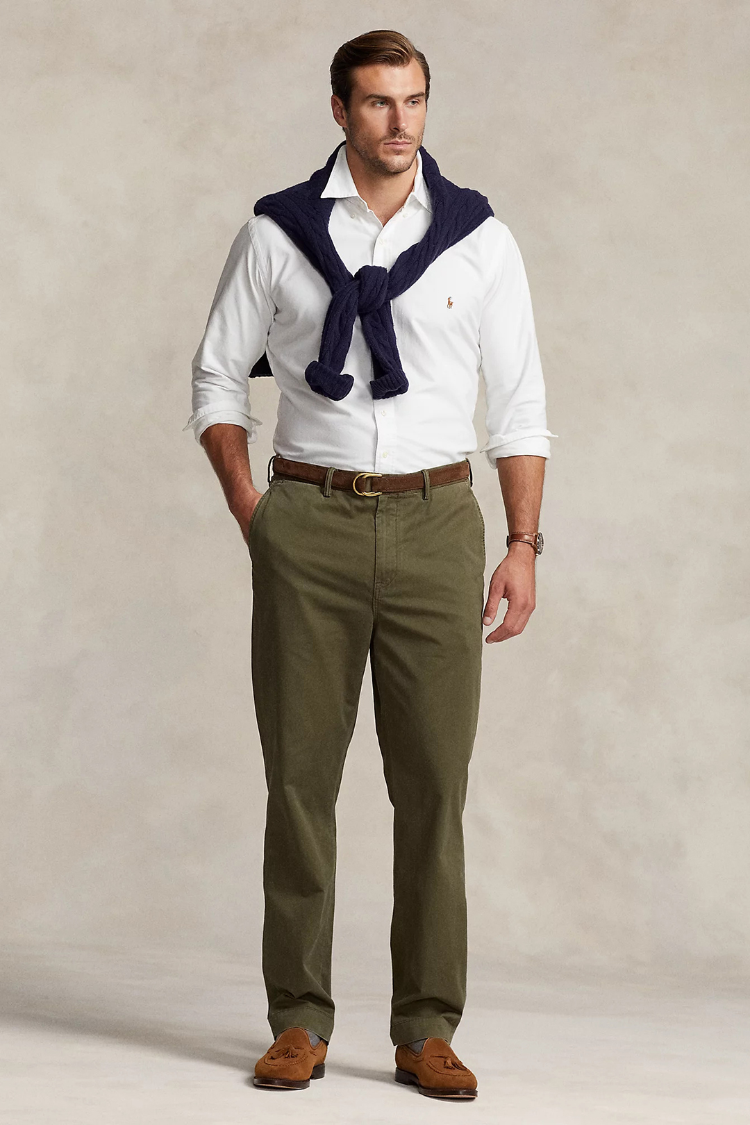White dress shirt, navy sweater draped over shoulders, olive green chinos, and brown suede loafers outfit